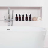 Bathroom setting with a white bathtub, faucet, and amber bottles on a shelf