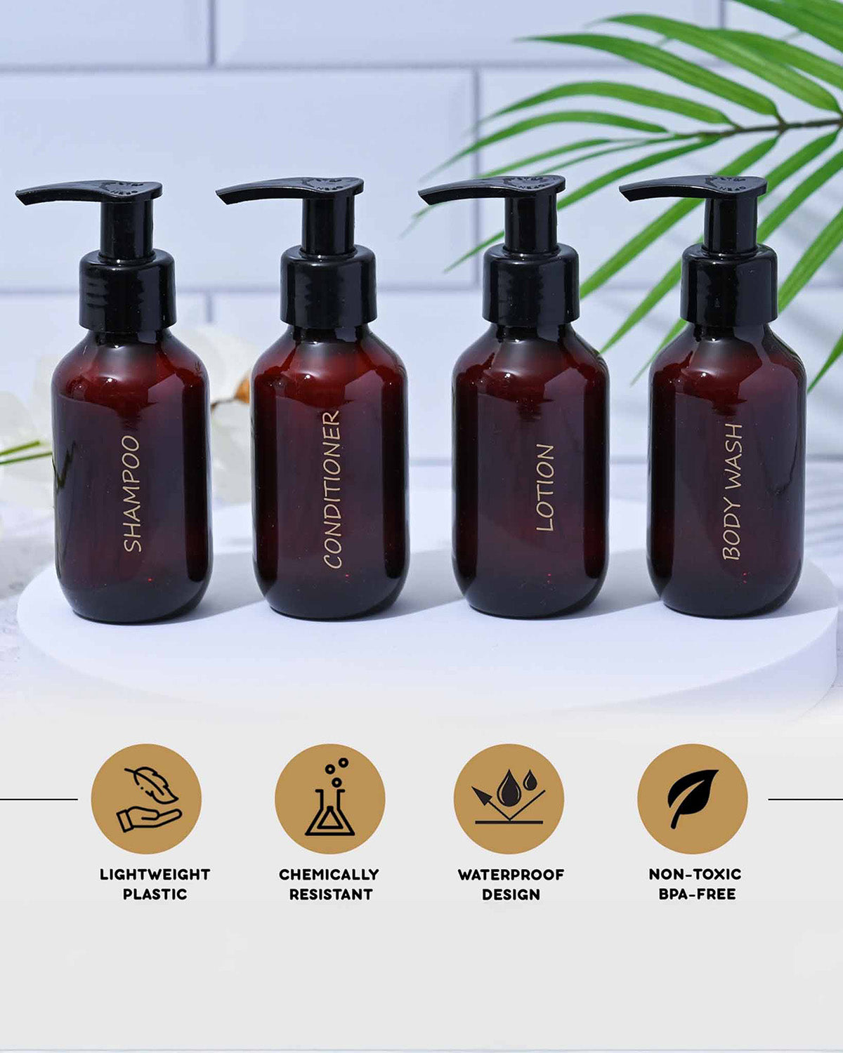 Set of four brown bottles labeled Shampoo, Conditioner, Lotion, and Body Wash on a white background with green leaves