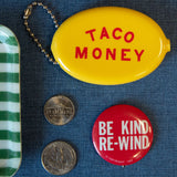 Yellow container labeled 'Taco Money' with a red button labeled 'Be Kind Re-Wind' on a blue textured background