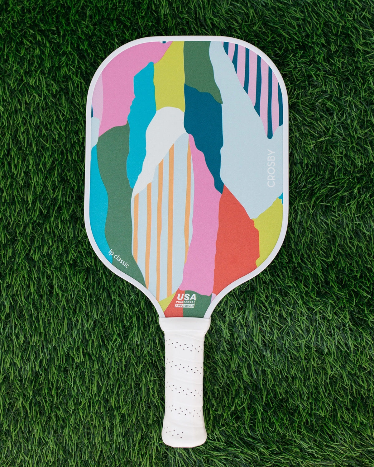 Colorful pickleball paddle on a green grass background