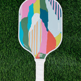 Colorful pickleball paddle on a green grass background