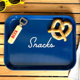 Blue tray with 'Snacks' text, bottle opener, and pretzel on a wooden surface