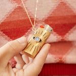Gold lighter with blue gemstone held by a hand against a red plaid background
