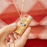 Gold lighter with blue gemstone held by a hand against a red plaid background