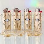 Four gold lighters with eye designs on a white background
