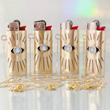 Four gold lighters with eye designs on a white background