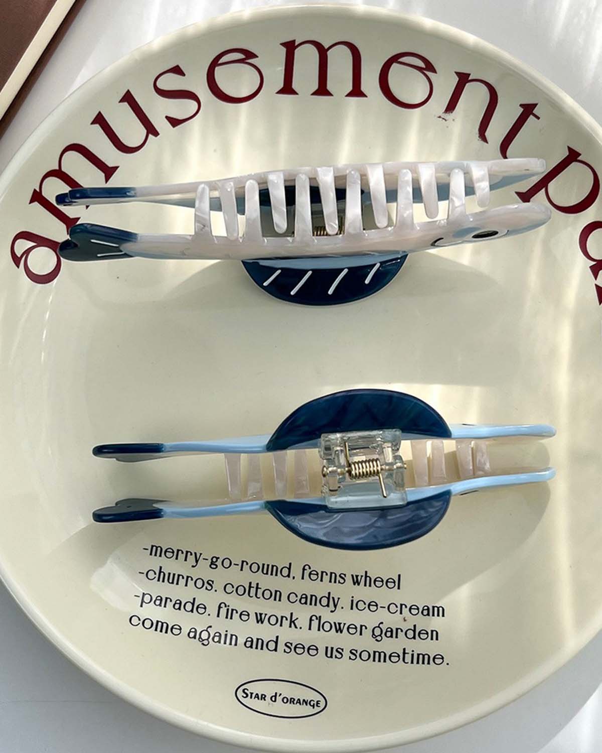 Two white combs with blue handles on a white plate with red text