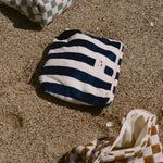 Striped bag and checkered shoes on sandy ground