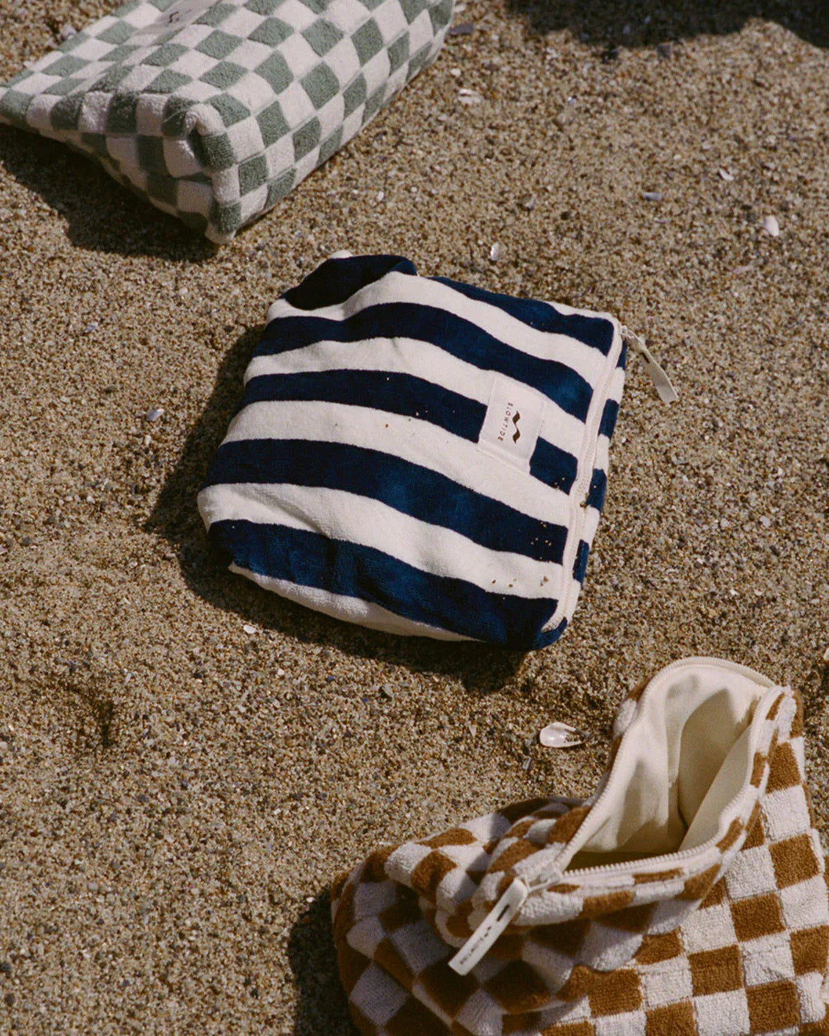 Striped bag and checkered shoes on sandy ground