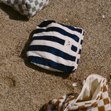 Striped bag and checkered shoes on sandy ground