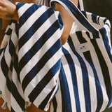 Two blue and white striped bags held by a person