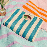 Palm fiber woven teal and tan striped bag on blanket