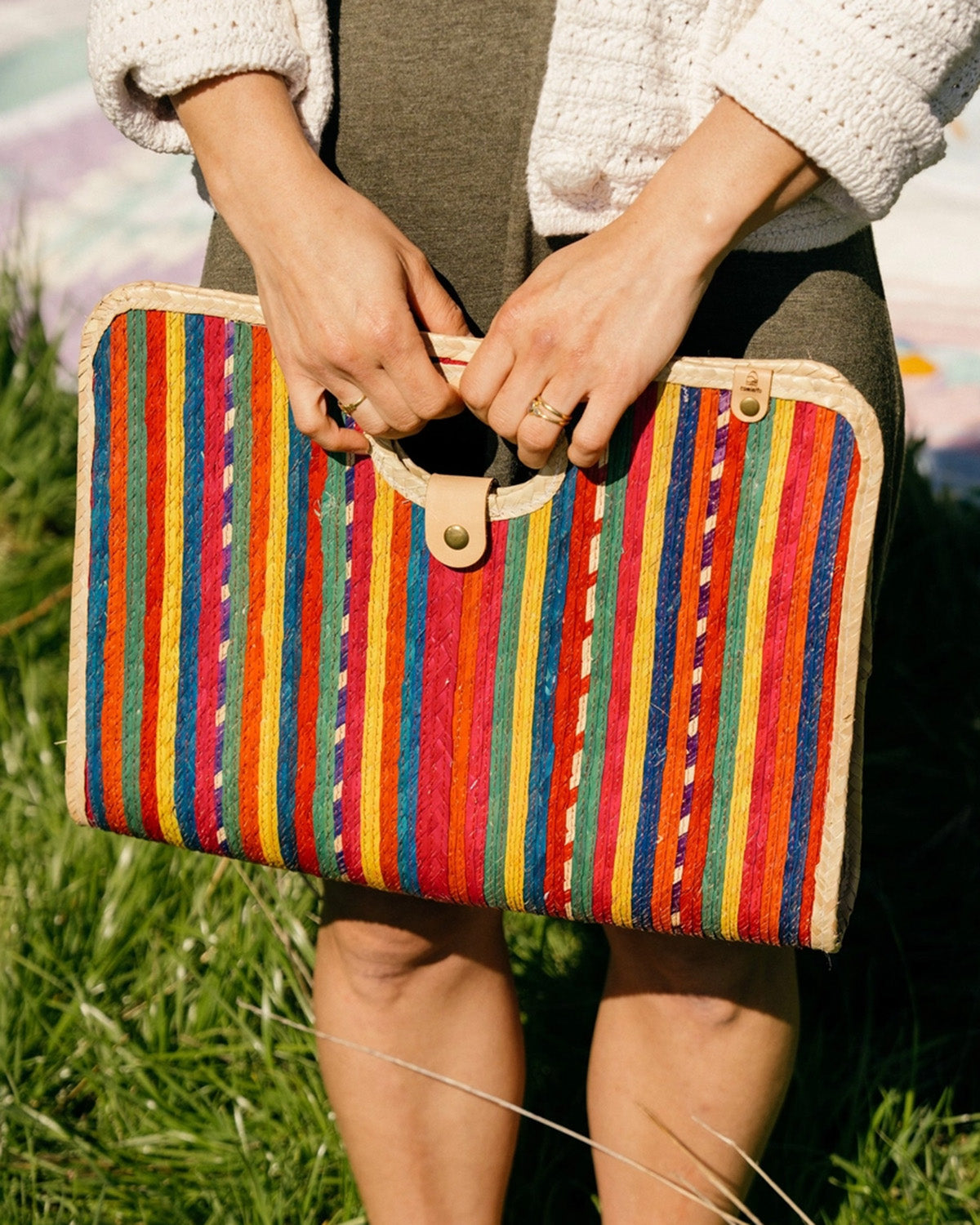 Model holding palm fiber woven red fiesta bag at angle