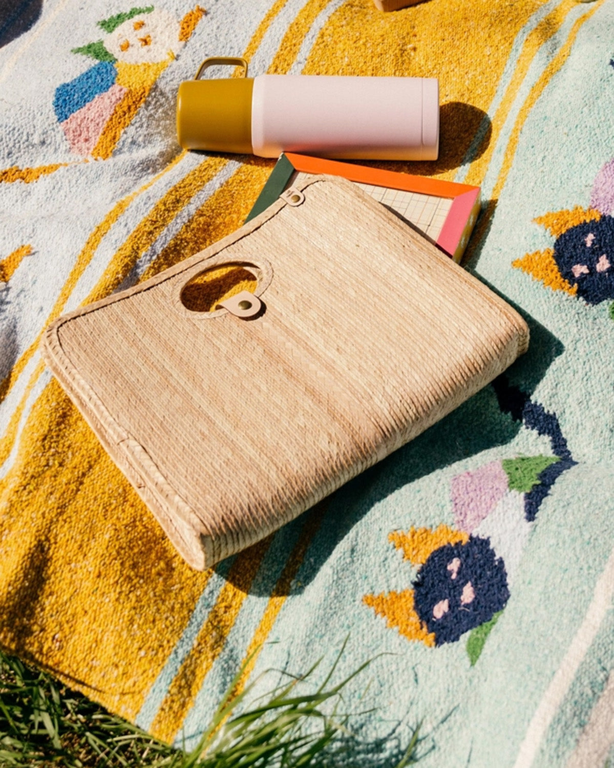 Palm fiber woven tan bag on blanket