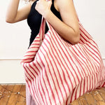 Person holding a red and white striped bag on a wooden floor