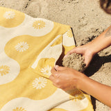 Yellow beach towel with floral pattern on sand