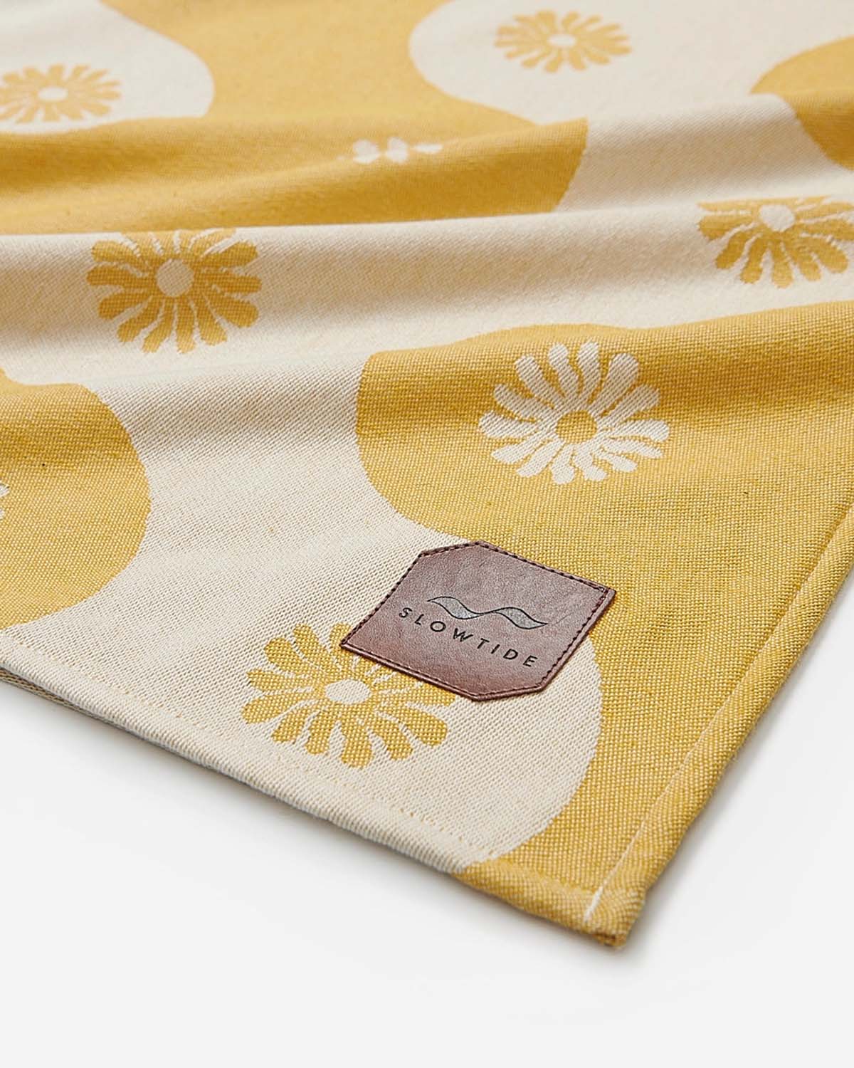 Yellow and beige fabric with floral patterns and a 'Slowtide' logo