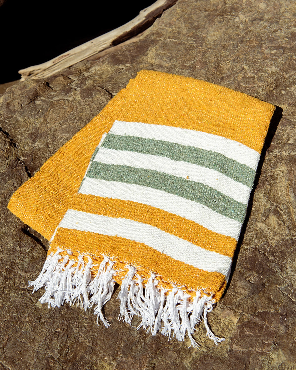 Yellow towel with green and white stripes on a stone surface