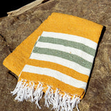 Yellow towel with green and white stripes on a stone surface