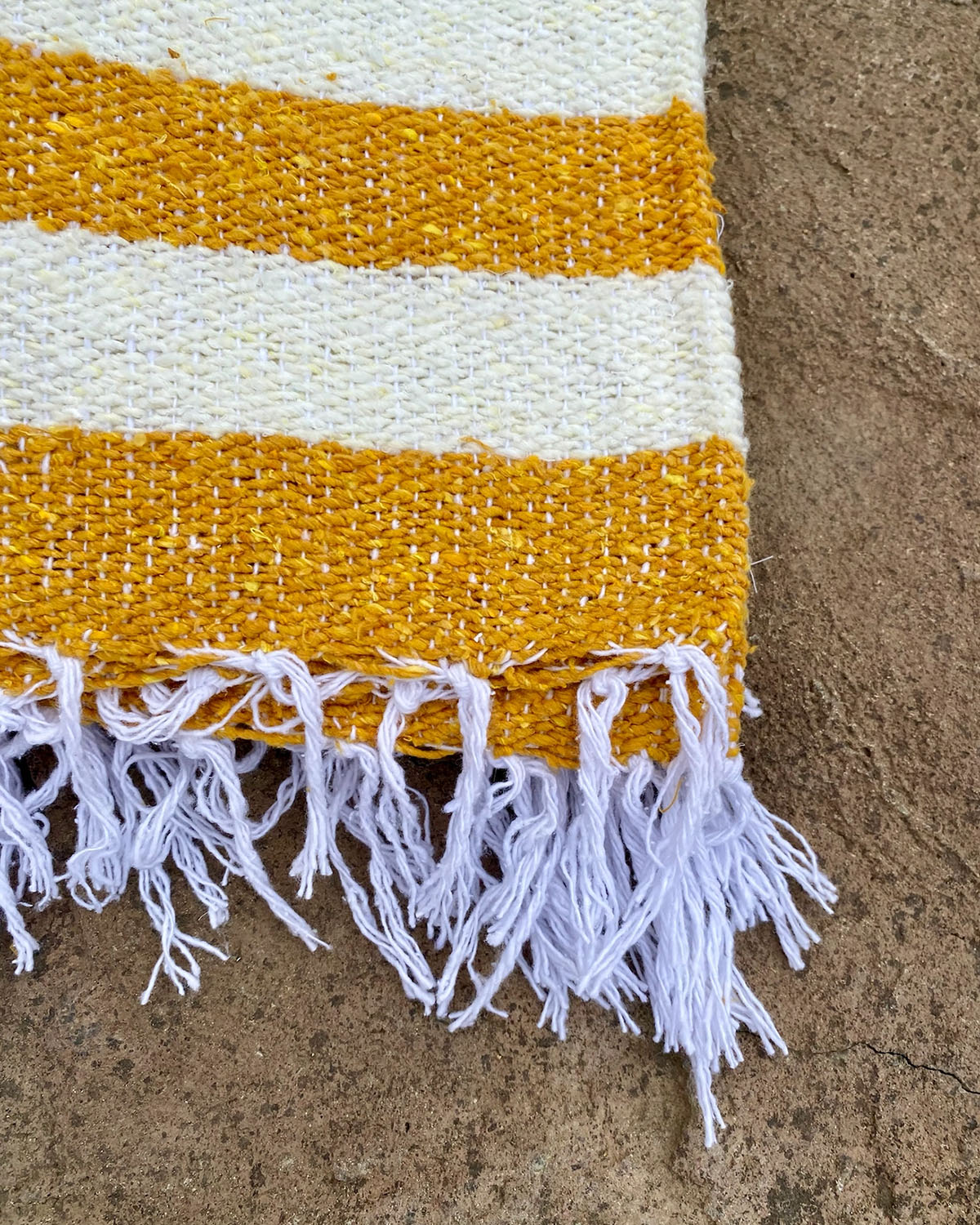 Striped rug with yellow and white stripes on a textured surface