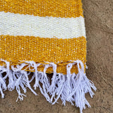 Striped rug with yellow and white stripes on a textured surface