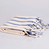 Folded towel with blue stripes and tassels on a light gray background