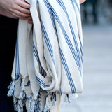 Person holding a white towel with blue stripes and tassels
