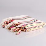Colorful striped towel with tassels on a gray background