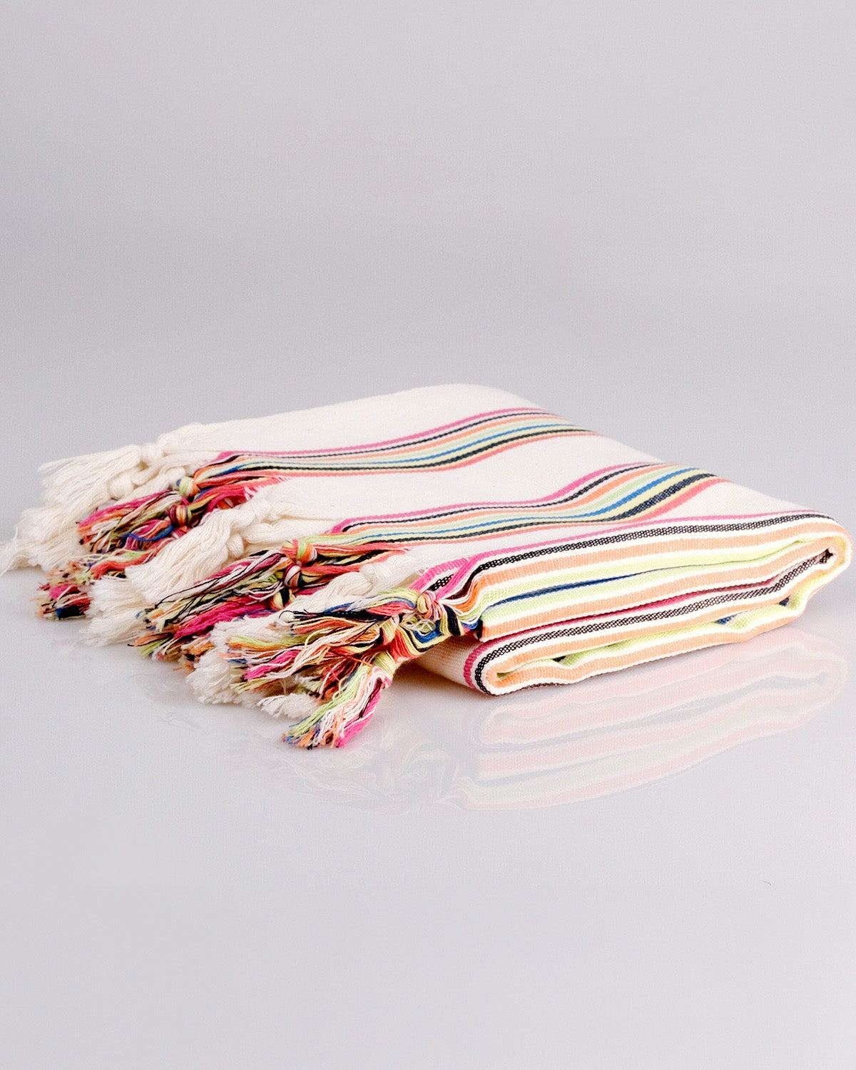 Colorful striped towel with tassels on a gray background