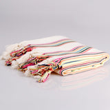 Colorful striped towel with tassels on a gray background