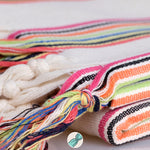 Colorful hand-knotted fringes on a textured fabric background