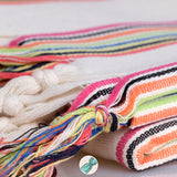 Colorful hand-knotted fringes on a textured fabric background