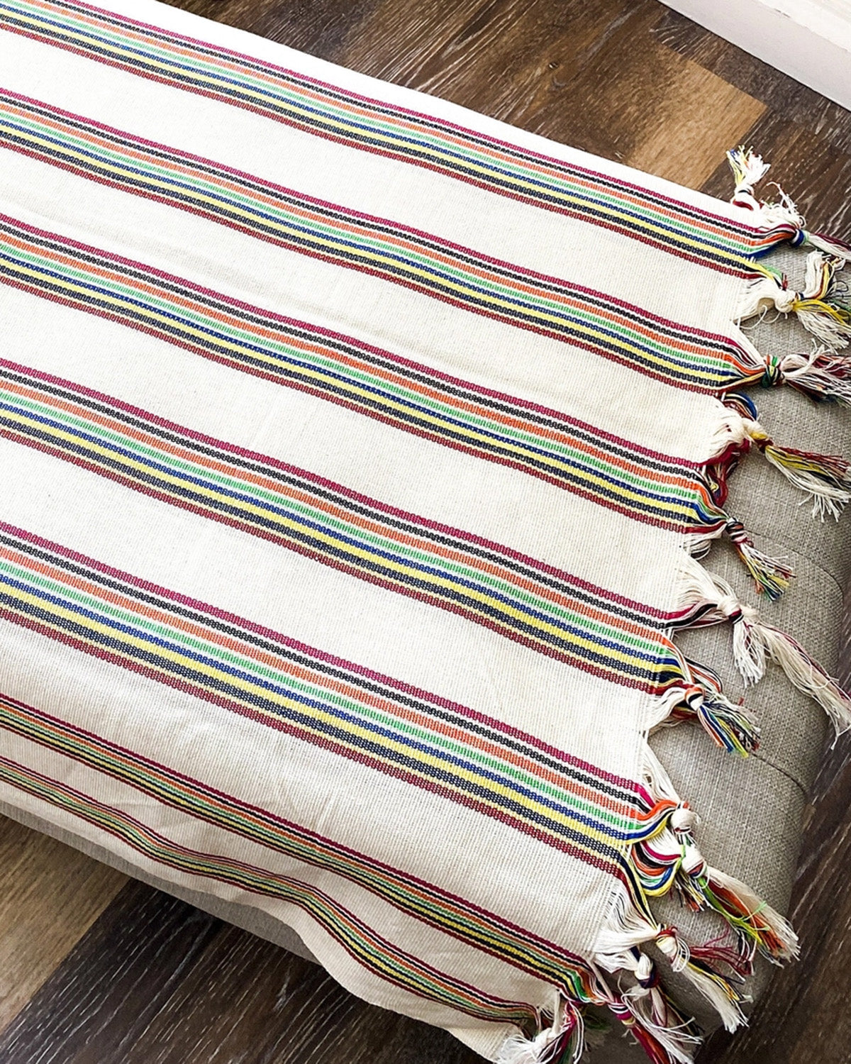 Striped table runner with tassels on a wooden surface