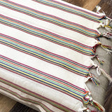 Striped table runner with tassels on a wooden surface