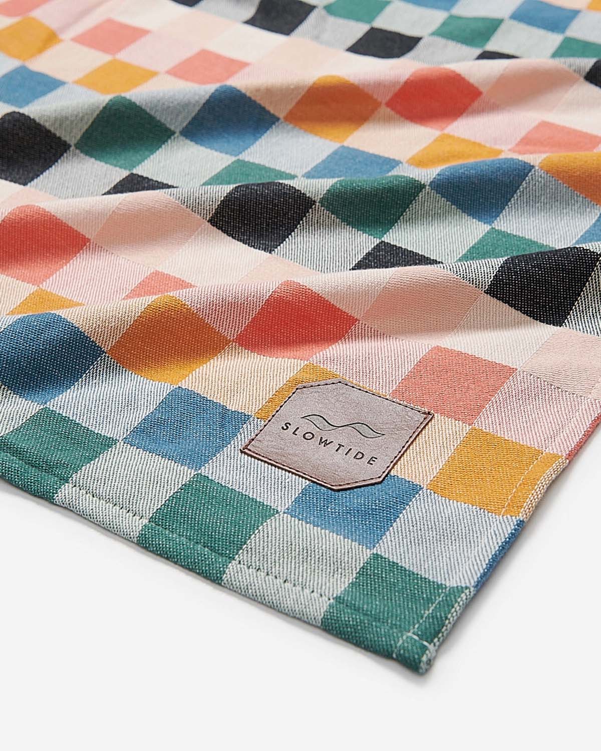 Colorful checkered fabric with a 'Slowtide' logo in the corner