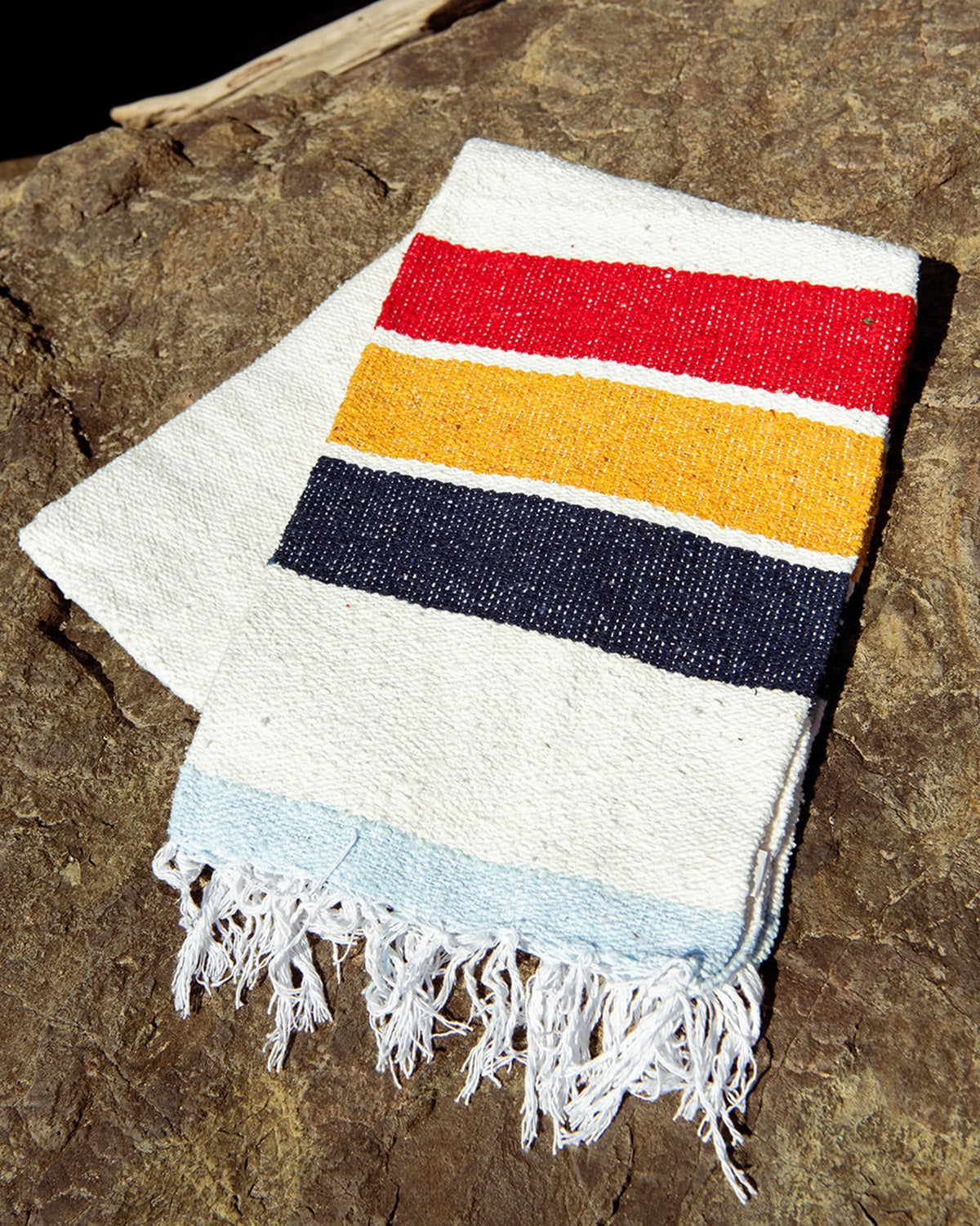 Striped towel with red, yellow, blue, and white on a stone surface