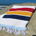Colorful striped towel on a sandy beach with ocean view