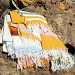 Colorful striped towel with tassels on a rocky surface