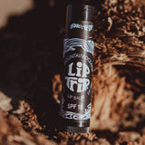 Lip balm tube labeled 'Lip Trip' on a natural background