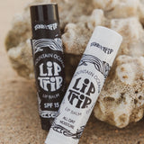 Two lip balm tubes from Mountain Ocean on a sandy background