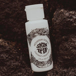 White bottle with black text and design on a dark stone background
