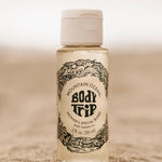 Bottle of Mountain Ocean Body Trip Mother's Special Blend body toning oil on a sandy background