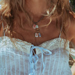 Close-up of a person wearing a white lace top and a necklace with multiple pendants