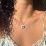 Close-up of a necklace with a pendant on a person wearing a light blue lace top