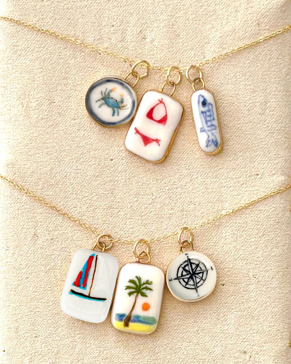 Necklace with four small ceramic charms on a textured beige background