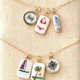Necklace with four small ceramic charms on a textured beige background