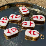 Small square charms with red bikini on a reflective surface