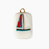 Small ceramic pendant with a sailboat design on a white background