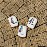 Three sailboat-shaped earrings on a textured surface