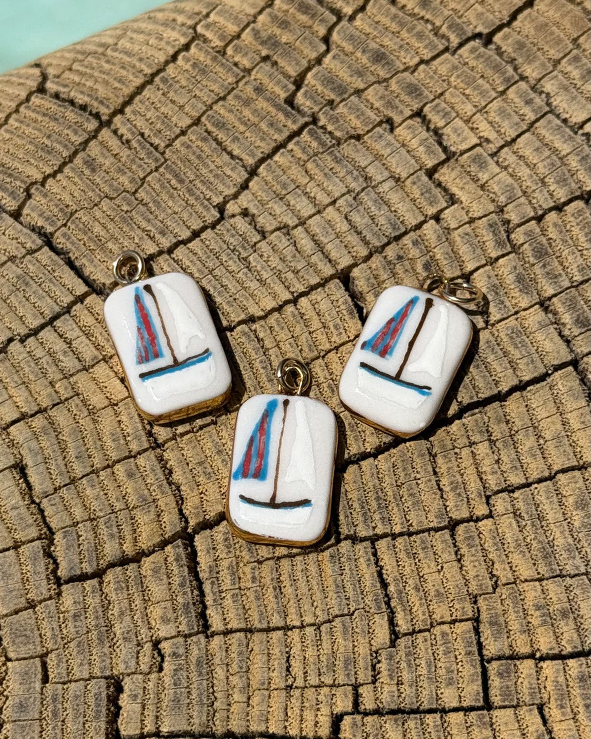 Three sailboat-shaped earrings on a textured surface